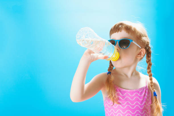 Little girl in swimsuit drinking water stock photo