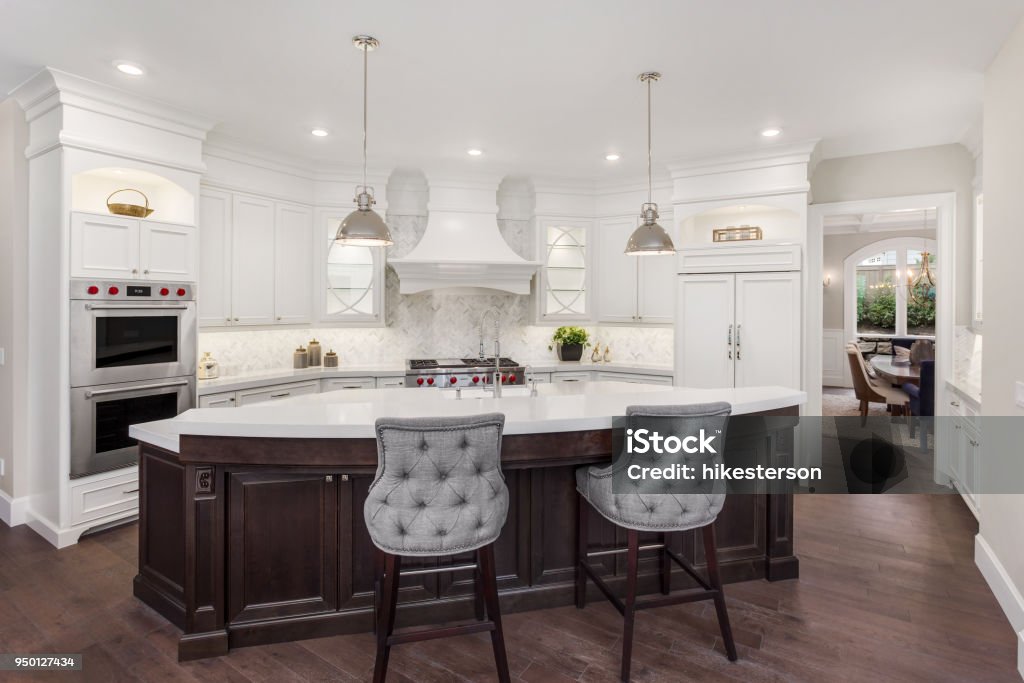 beautiful kitchen in new luxury home with island, pendant lights, and hardwood floors. Has partial view of dining room kitchen in newly constructed luxury home Kitchen Stock Photo