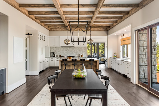 Stunning kitchen and dining room in new luxury home. Wood beams and elegant pendant lights accent this beautiful open-plan dining room and kitchen