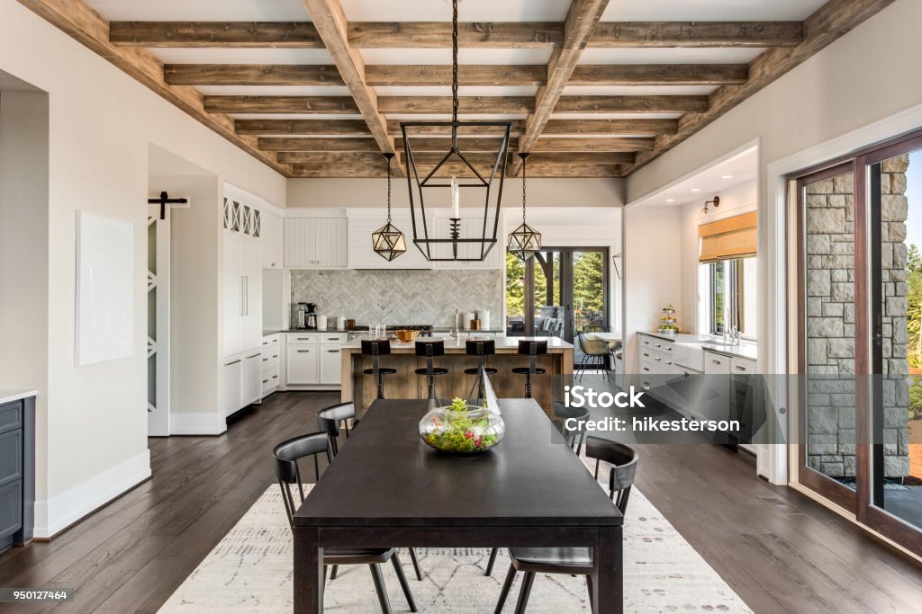 Stunning kitchen and dining room in new luxury home. Wood beams and elegant pendant lights accent this beautiful open-plan dining room and kitchen dining room and kitchen in new luxury home Kitchen Stock Photo