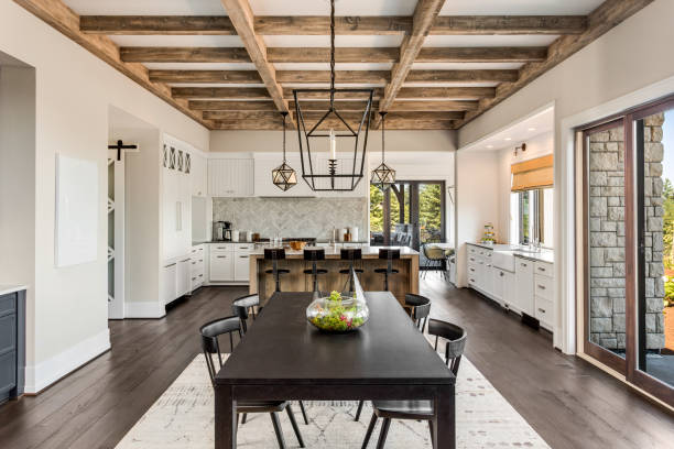 Stunning kitchen and dining room in new luxury home. Wood beams and elegant pendant lights accent this beautiful open-plan dining room and kitchen dining room and kitchen in new luxury home home showcase interior stock pictures, royalty-free photos & images