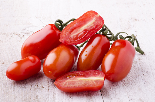 bunch of freshly picked San Marzano tomatoes laid down on a light wooden table