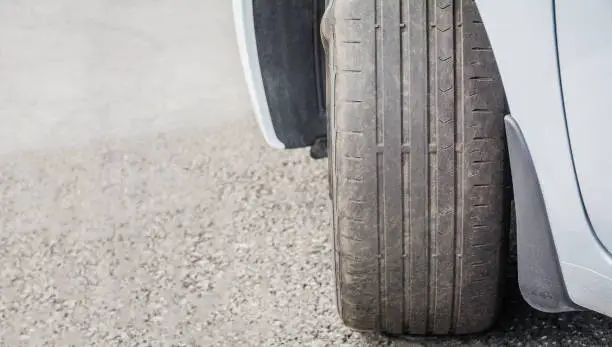 Photo of Badly worn out car tire tread and damaged bulb like side due to wear and tear or because of poor tracking or alignment of the wheels, dangerous for driving and unsafe, not safe for use, copy space.