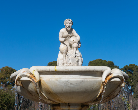 Cupid statue in the fountain of the Garden of Roses in Buen Retiro Park. Parque De Las Rosas in Spanish) in Botanical Garden in Park of Retiro. Madrid, Spain.