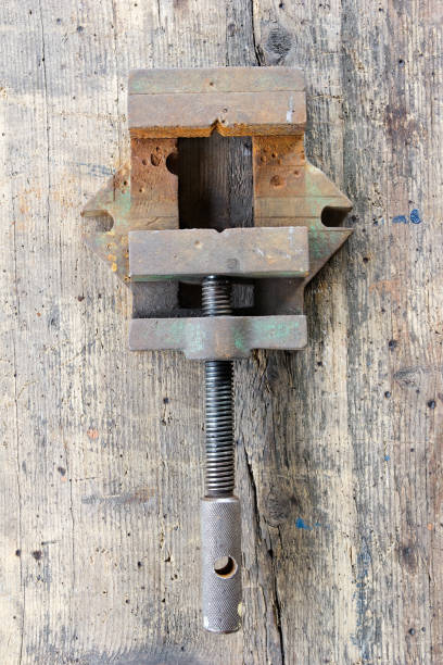 istock Old, dirty screw press against wooden plank. 950152692