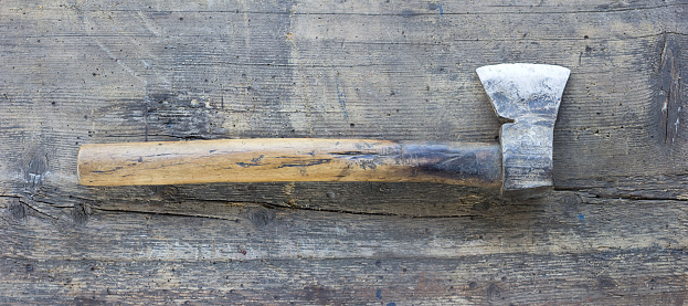 Old axe against wooden plank. Tool series.