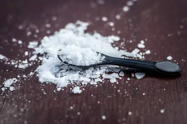 Photo of Close up of aurvedic herb camphor powder in a small spoon on brown wooden surface in dark Gothic colors is helps in Prevents Skin Infections,Eliminates Gas,Reduces Nervous Disorders,Increases Libido.