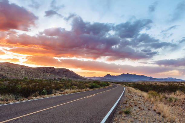 Road through dramatic sunset and sky over desert landscape Two lane highway at dusk in the Chisos Mountains in Big Bend National Park, Texas gulf coast states photos stock pictures, royalty-free photos & images