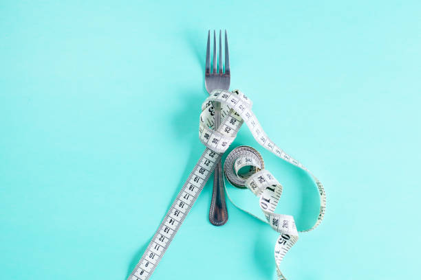 istock Measure tape and fork on wooden table as a diet concept 950183776