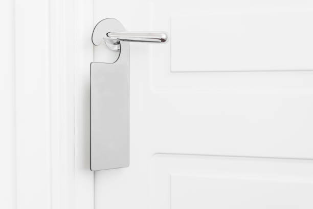 istock Door knob with empty label on a door handle for your text. Empty white flyer mockup hang on door handle. Leaflet design on entrance doorknob. Dont disturb sign. Hotel room clear hanger. blank 950186028