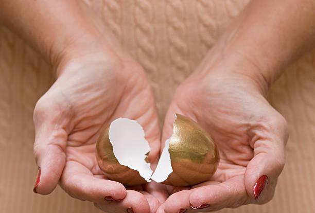 broken ruhestand dreams - animal egg gold human hand nest egg stock-fotos und bilder