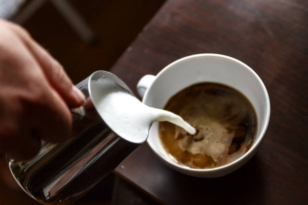 istock man pouring into a cup of coffee with milk 950196300