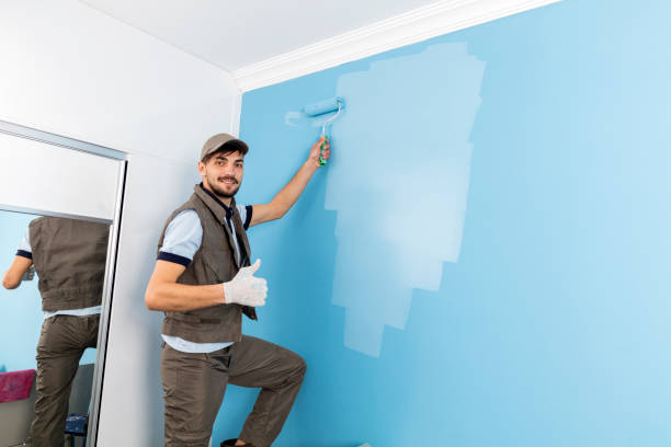 istock Young man painting a wall blue with a roller 950196450