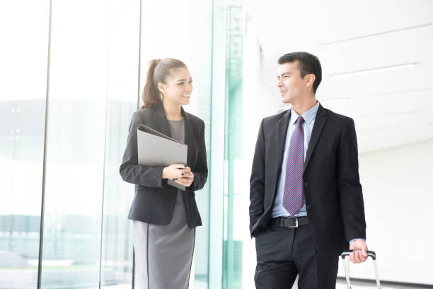 istock Businessman walking and pulling luggage handle while talking with a businesswoman 950201080