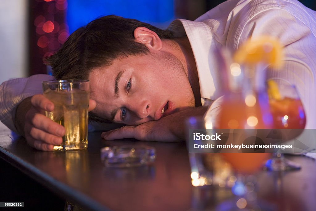 Drunk young man resting head on bar counter  Cocktail Stock Photo