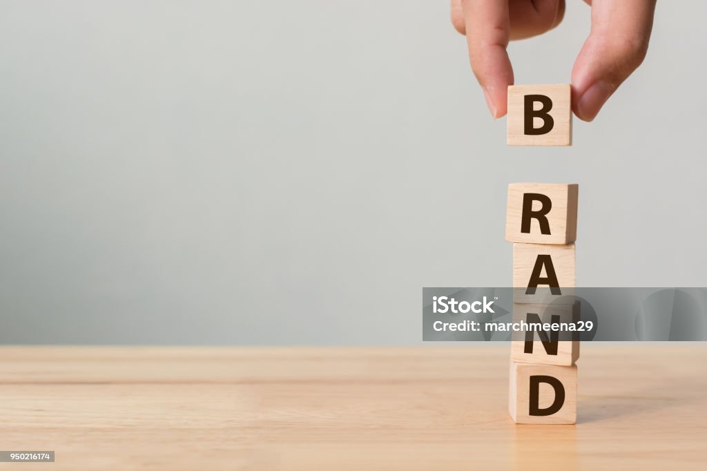 Hand des männlichen Putten Holz Würfel-Block mit Wort "Marke" auf Holztisch. Markenbildung für Erfolgskonzept - Lizenzfrei Werbung Stock-Foto