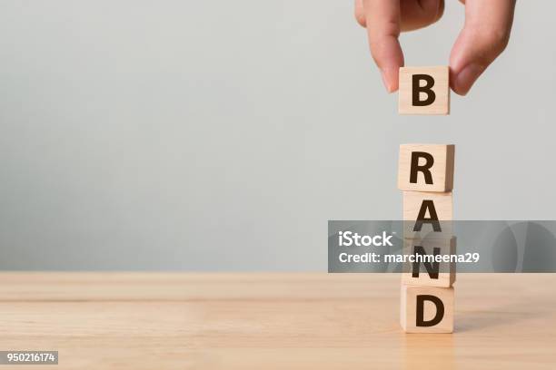 Hand Of Male Putting Wood Cube Block With Word Brand On Wooden Table Brand Building For Success Concept Stock Photo - Download Image Now