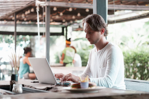 istock Young male freelancer sitting in cafe working in laptop 950223620