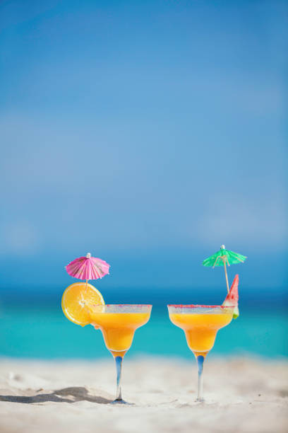 Tropical fruit cocktail drinks on sand in a Caribbean island turquoise beach
