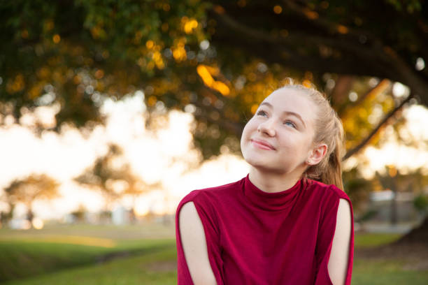 Australian Teenage Girl Looking Up Australian teenage girl at the park looking up thinking, dreaming, contemplating. 15 year old blonde girl stock pictures, royalty-free photos & images