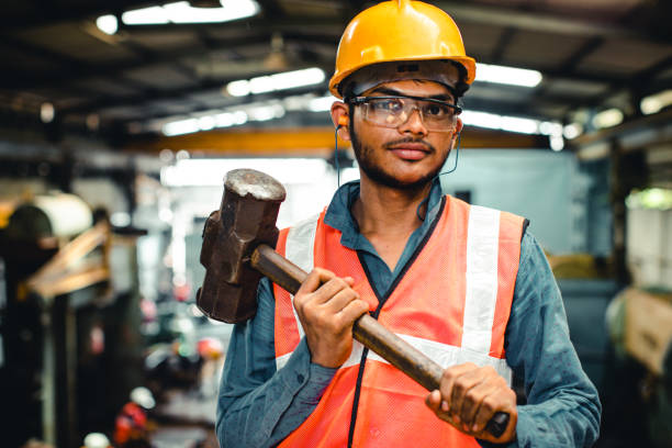 istock Young factory employee holding up a heavy hammer while looking into the camera. 950229480