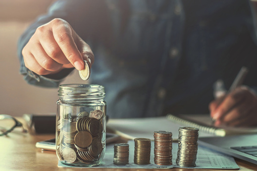 business woman hand holding coins puting in glass. concept finance and accounting saving