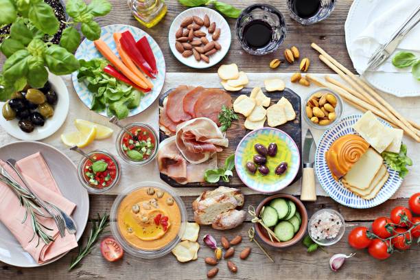 istock Mediterranean appetizers table concept. Diner table with antipasto selection: cured meat and salami, gazpacho soup, jamon, olives, cheese, hummus and vegetables. 950249388