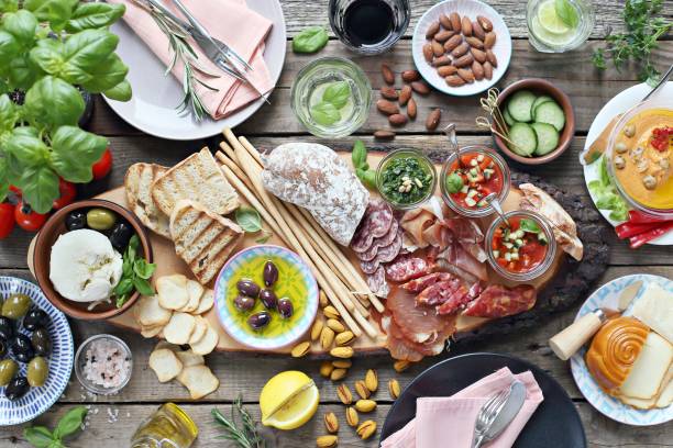 istock Mediterranean appetizers table concept. Diner table with antipasto selection: cured meat and salami, gazpacho soup, jamon, olives, cheese, hummus and vegetables. 950249478