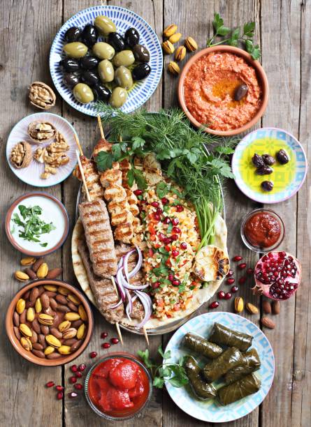 istock Middle eastern, arabic or mediterranean dinner table with grilled lamb kebab, chicken skewers  with roasted vegetables and appetizers variety serving on rustic outdoor table. 950251018