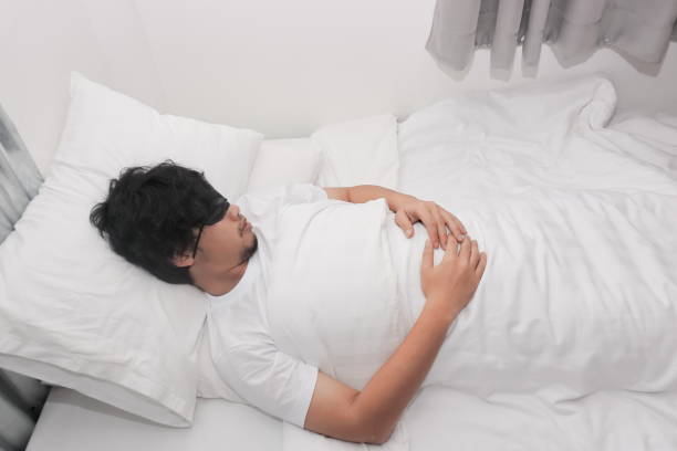 istock Young Asian man with blindfold eye mask sleeping on the white bed in bedroom. 950253058