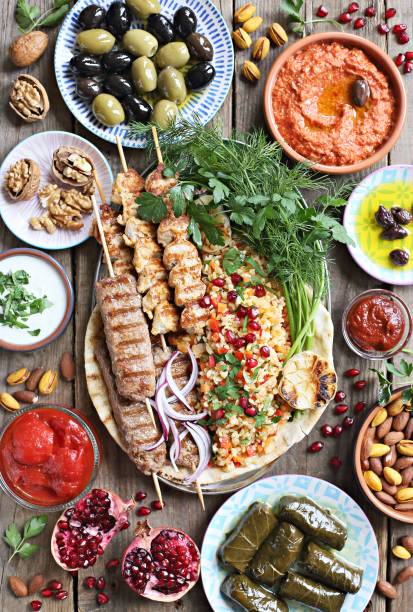 istock Middle eastern, arabic or mediterranean dinner table with grilled lamb kebab, chicken skewers  with roasted vegetables and appetizers variety serving on rustic outdoor table. 950253088