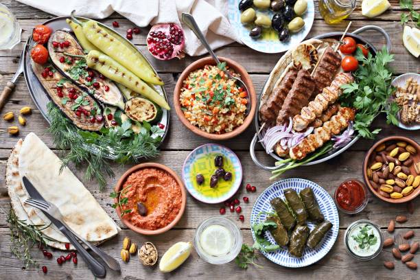 mesa del medio oriente, árabe o mediterránea con kebab de cordero, pinchos de pollo con verduras asadas y variedad de aperitivos que sirve en la mesa de jardín rústica. - comida verano fotografías e imágenes de stock