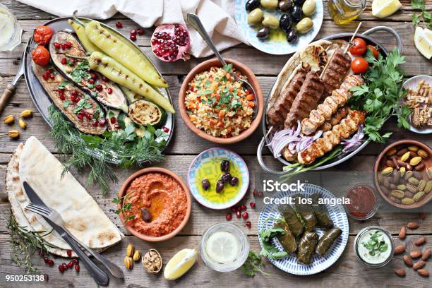 Middle Eastern Arabic Or Mediterranean Dinner Table With Grilled Lamb Kebab Chicken Skewers With Roasted Vegetables And Appetizers Variety Serving On Rustic Outdoor Table Stock Photo - Download Image Now
