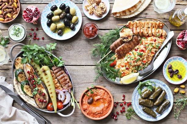 istock Middle eastern, arabic or mediterranean dinner table with grilled lamb kebab, chicken skewers  with roasted vegetables and appetizers variety serving on rustic outdoor table. 950253152