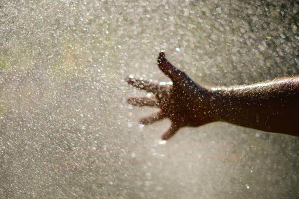 istock Water drops and hand - holding hand in water splash - 950261764