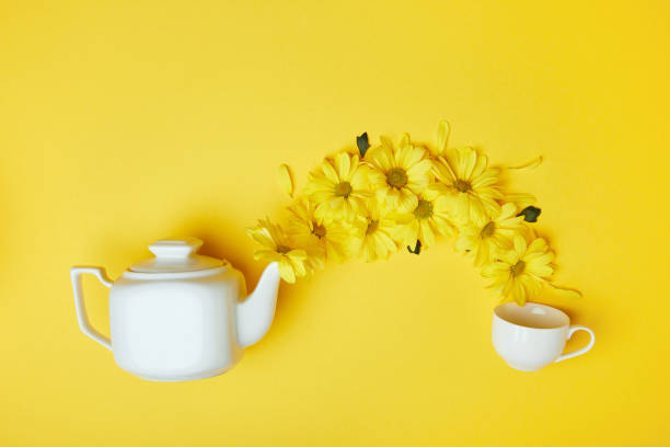 istock Yellow chrysanthemums pouring into cup from white pot isolated on yellow 950265142