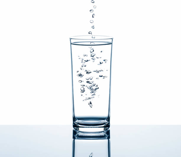 istock Fresh drinking water dropping into glass with bubbles on white background 950265394