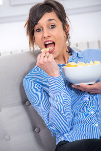 istock pretty young brunette woman eating chips 950267170