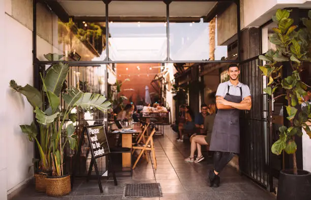 Photo of Young male business owner standing outside hipster urban café