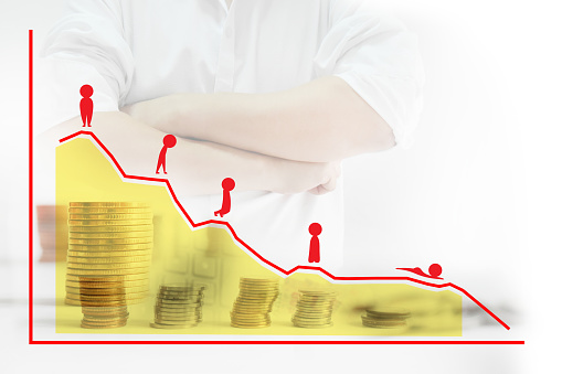 Background blur businessman wearing cross one's arm white shirt , Foreign currency sorted into piles and rows.Foreground is red cartoon showing a negative attitude and graphs, statistics.