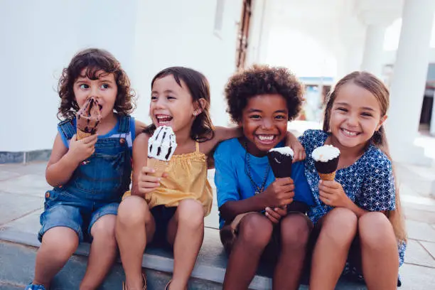 Photo of Group of cheerful multi-ethnic children eating ice-cream in summer