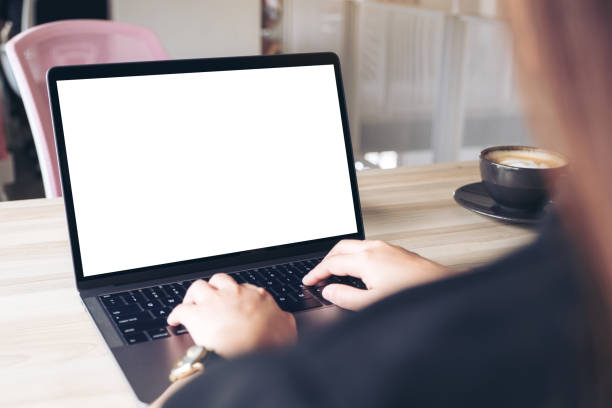 istock Mockup image of a businesswoman using and typing on laptop with blank white desktop screen with coffee cup on wooden table in office 950280850