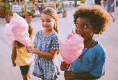Little multi-ethnic children eating cotton candy at amusement park