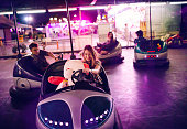 Teenage girl in bumper cars with teddy bear and friends