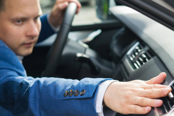 man in a blue suit adjusts the air intake in the car man in a blue suit adjusts the air intake in the car car door panels stock pictures, royalty-free photos & images