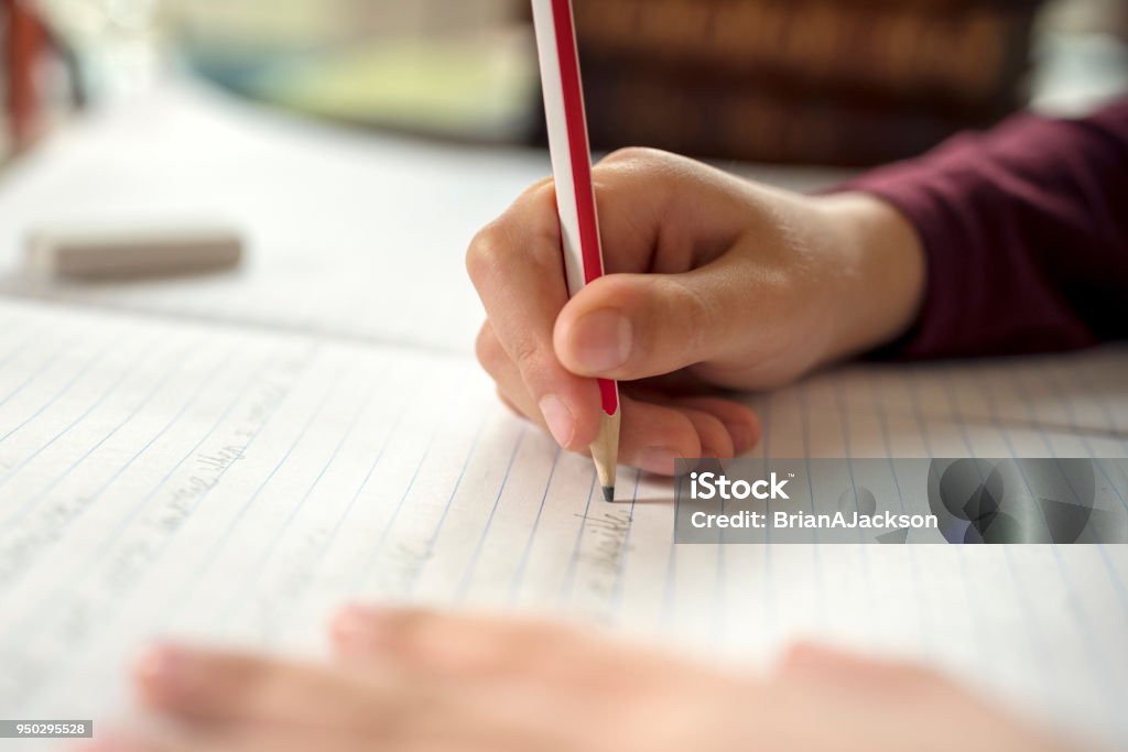 Boy doing his school work or homework Boy writing in a notepad doing his school work spelling or homework Writing - Activity Stock Photo