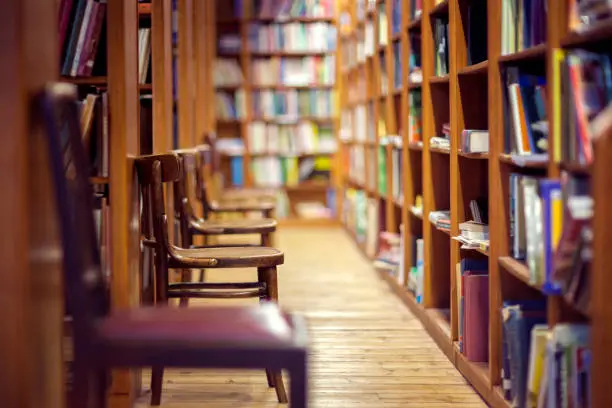 Photo of Library with books on shelf and empty chairs