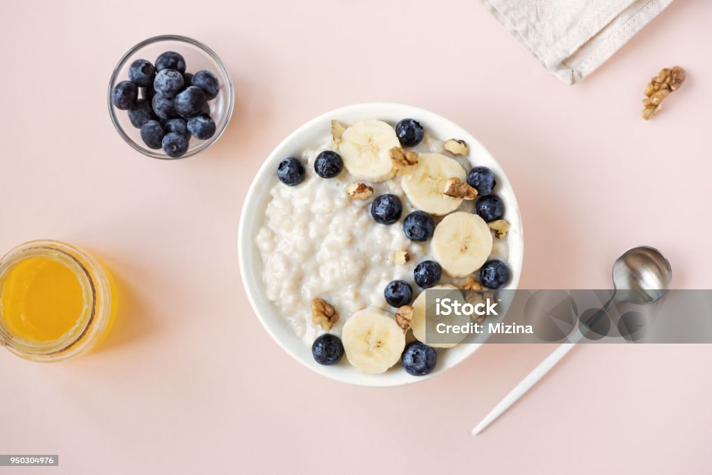 Oatmeal porridge Oatmeal porridge with walnuts, blueberries and banana in bowl on pink - healthy organic breakfast, oats with fruits, honey and nuts Porridge Stock Photo