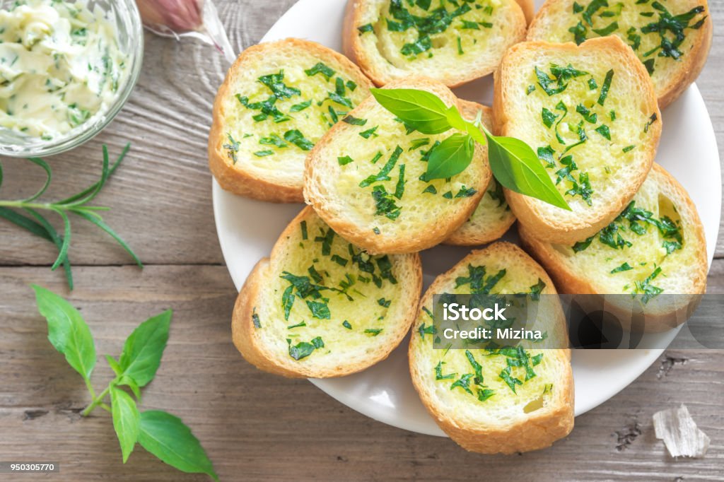 Garlic bread with herbs Toasted bread with garlic and herbs with ingredients over wooden background, copy space. Appetizer Stock Photo