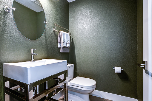 Dark Gray powder room features chrome washstand with white sink next to toilet.